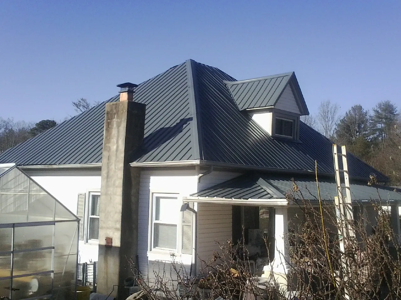 Dark blue standing seam metal roof on a white farmhouse with dormer — Slate & Tile Roof Repair by Roofing Brothers in Veyo
