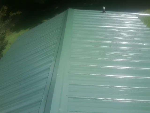 New green metal panels meeting at the ridge of a roof — Flat Roof Repair work by our crew in Veyo