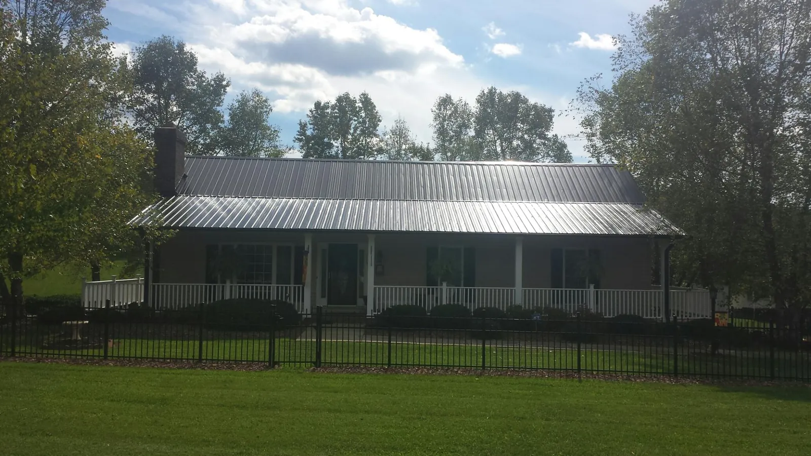 Gray metal roof on a brick ranch with a full width front porch — Gutter Guard Installation work by our crew in Veyo