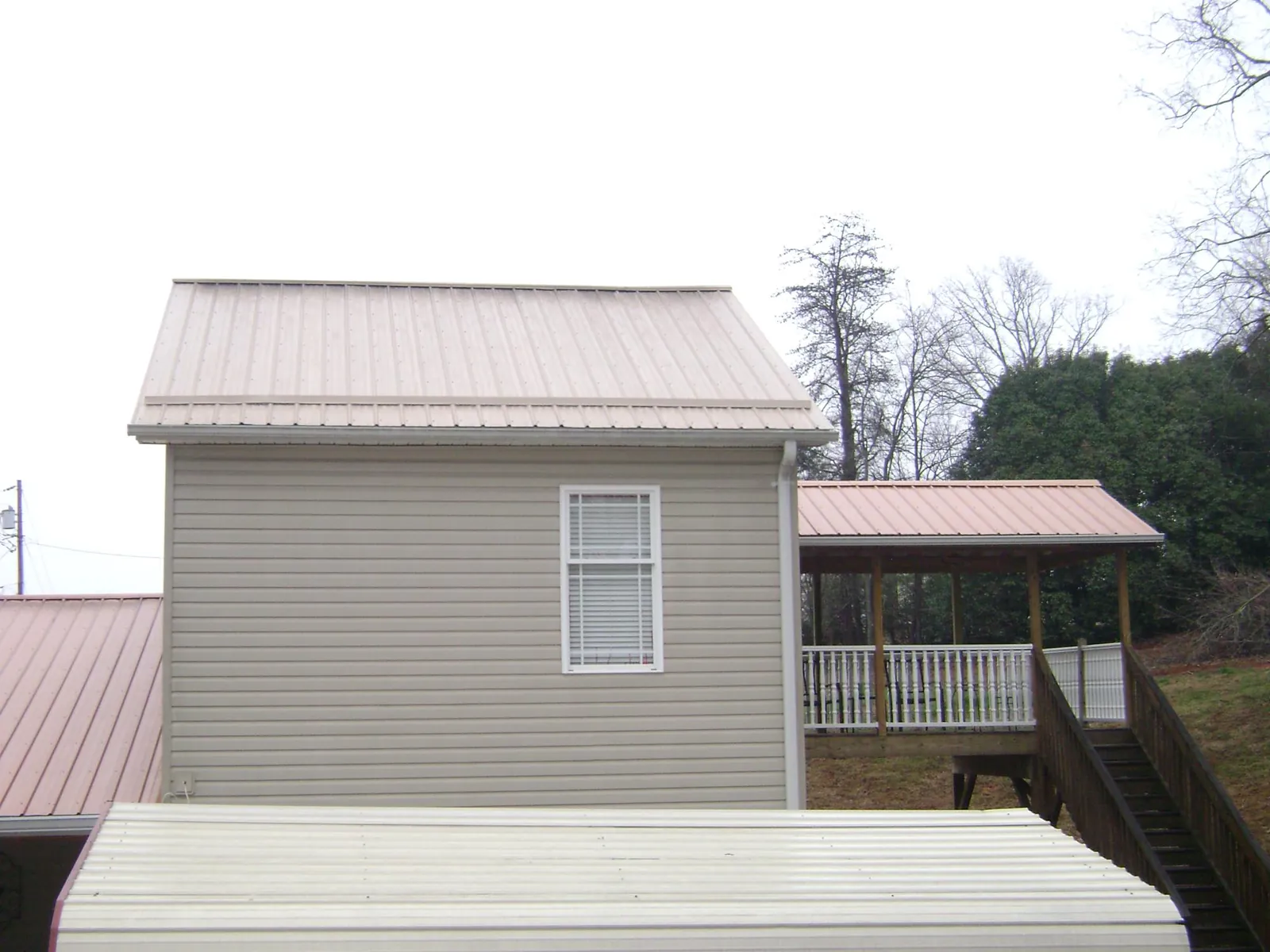 Tan metal roofs on a two story addition and attached porch, from a Roof Replacement job in Veyo