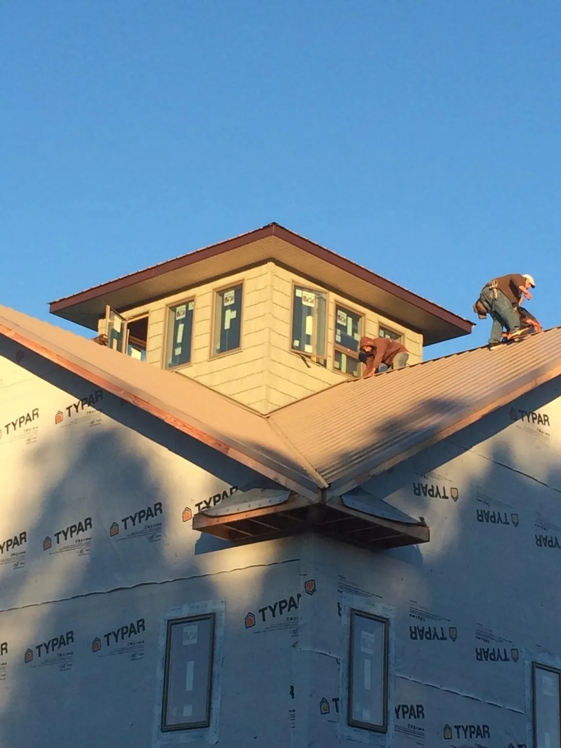 Roofers working around a rooftop cupola on a new metal roof at sunset — Roof Waterproofing in Veyo by Roofing Brothers